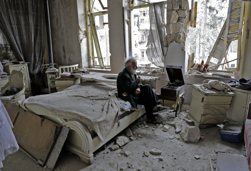 2017年，叙利亚阿勒颇，70岁的阿布·奥马尔(Abu Omar)在被毁的卧室里抽着烟斗听音乐